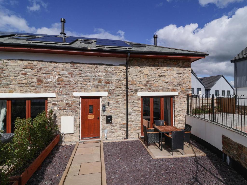 a brick house with a wooden door and a patio at Butterfly Days in Bideford