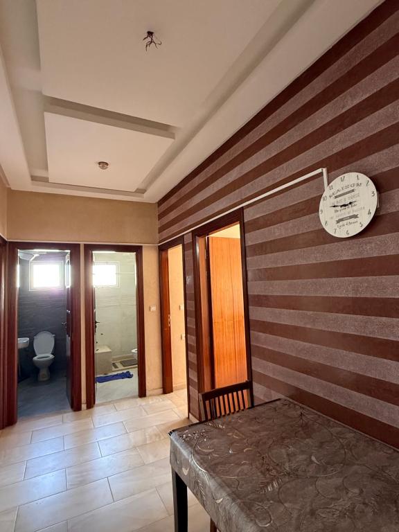 a room with a table and a clock on a wall at Appartement Ovalley SAFI in Safi
