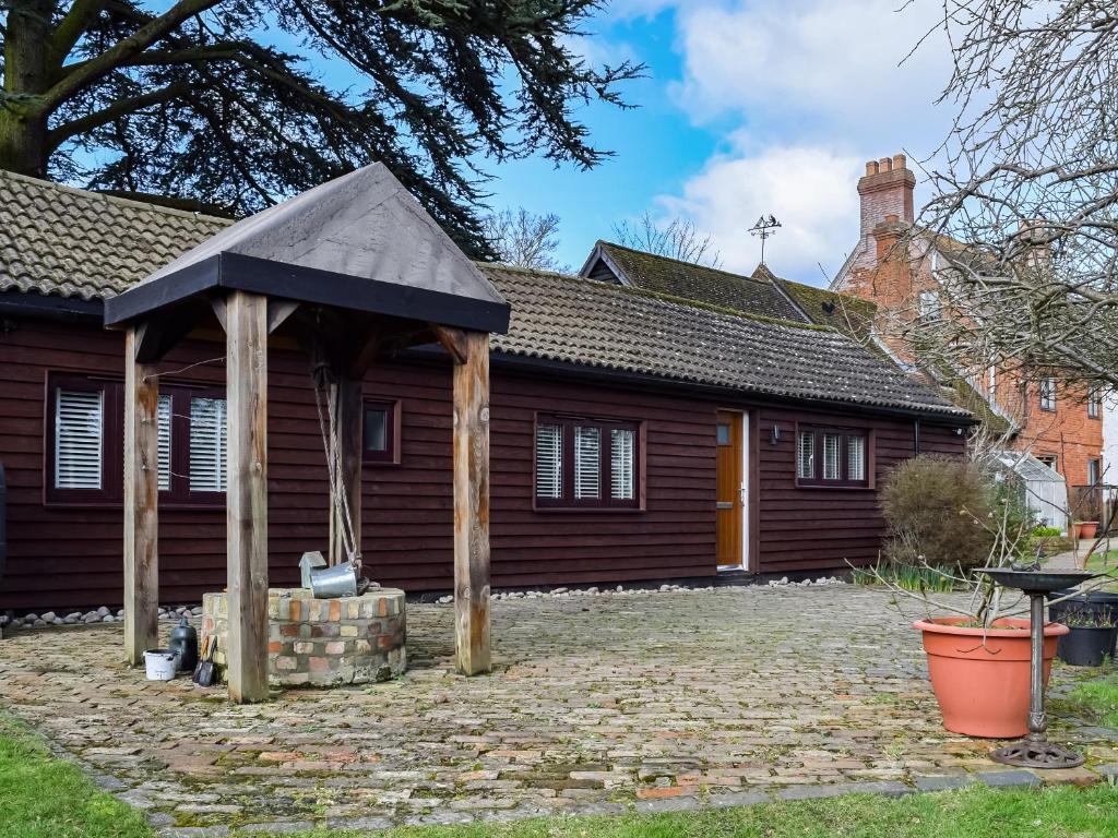 a house with a pitched roof and a patio at Brooklands Farm Cottage in Biggleswade