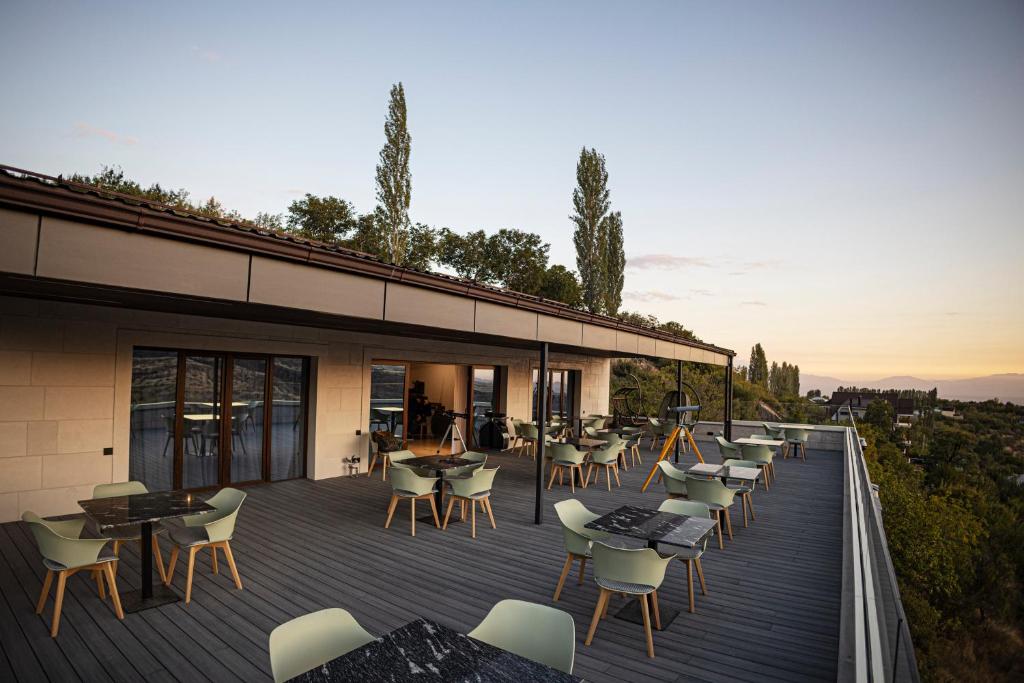 um deque com cadeiras e mesas num edifício em Château Byurakan Hotel em Byurakan