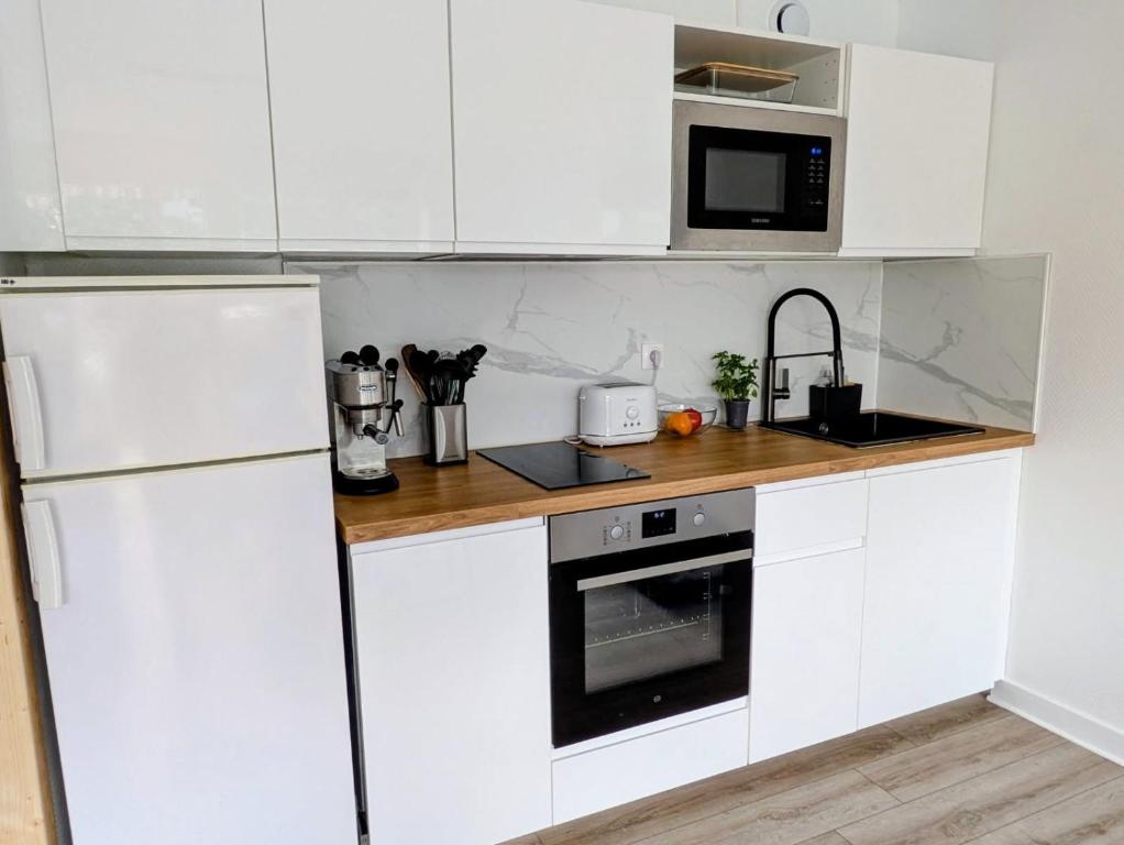 a kitchen with white cabinets and a white refrigerator at La Cahute des Tamaris in Mimizan-Plage