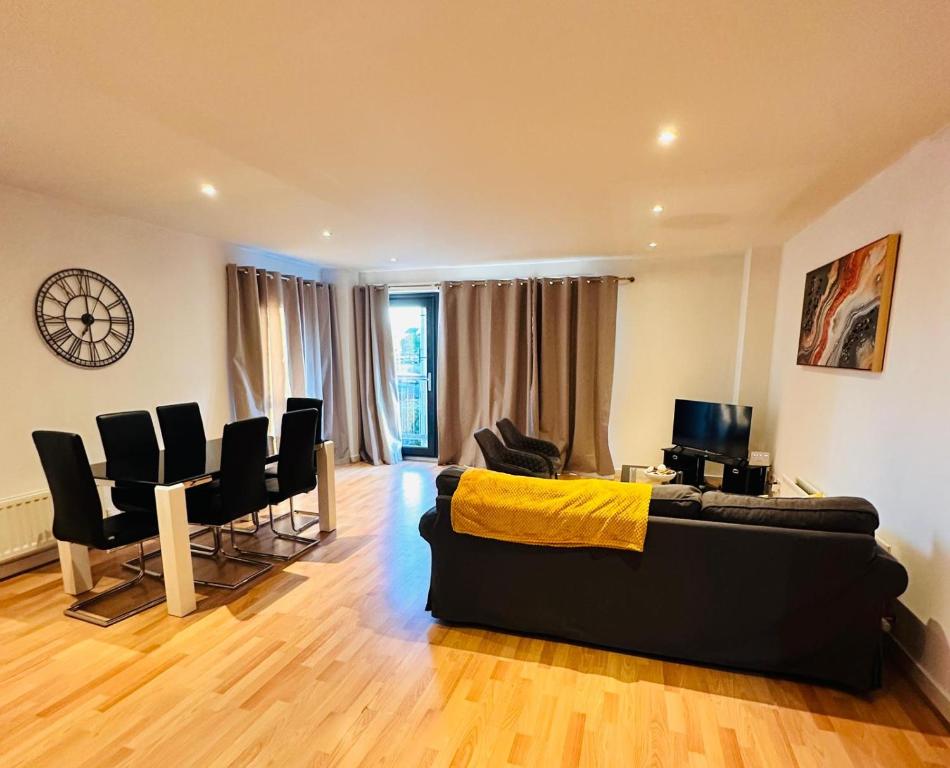 uma sala de estar com um sofá preto e cadeiras em Harbour Horizons em Edinburgo