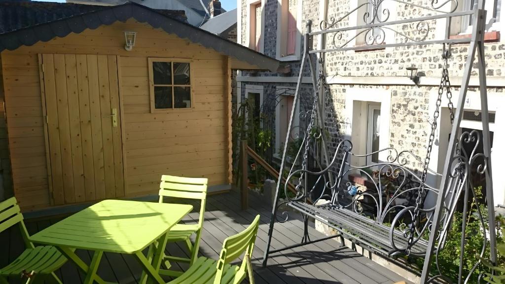 a patio with a swing and a table and chairs at Chez Isa Maison de pêcheur Etretat in Yport