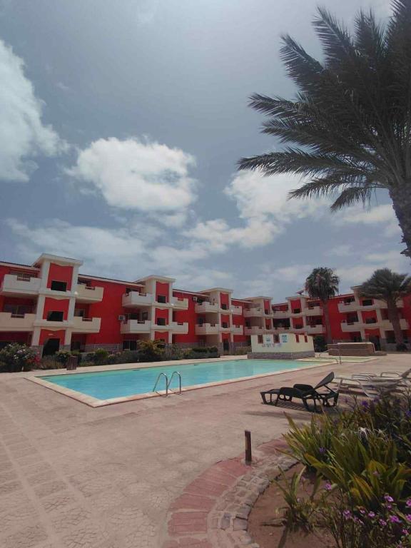 un grande complesso di appartamenti con piscina e palma di Casa Minuxa a Santa Maria