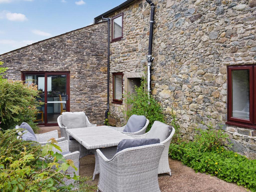 a table and chairs in front of a stone building at The Martins - Uk47429 in Bewaldeth