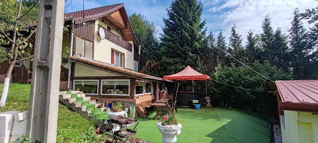una casa con un cortile verde con una tenda rossa di Vila Dona a Budeni