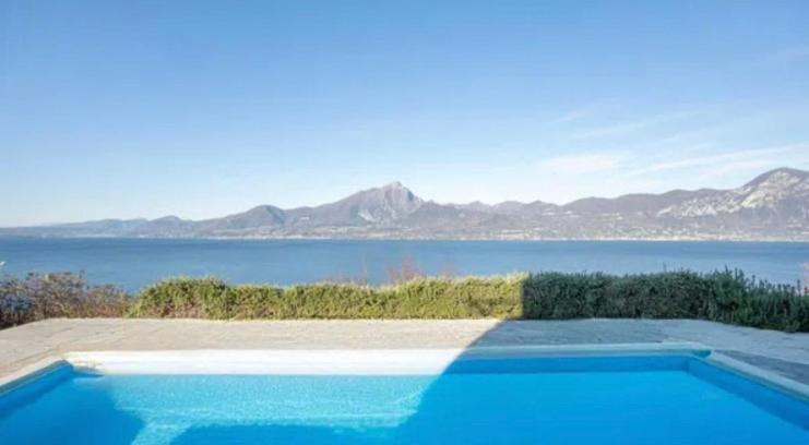 a blue swimming pool with a view of the water at Suite Incanto lago di Garda in Torri del Benaco