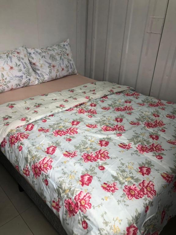 un letto con una coperta bianca con fiori rossi sopra di Kitnet Nova e Aconchegante a Cachoeira do Sul