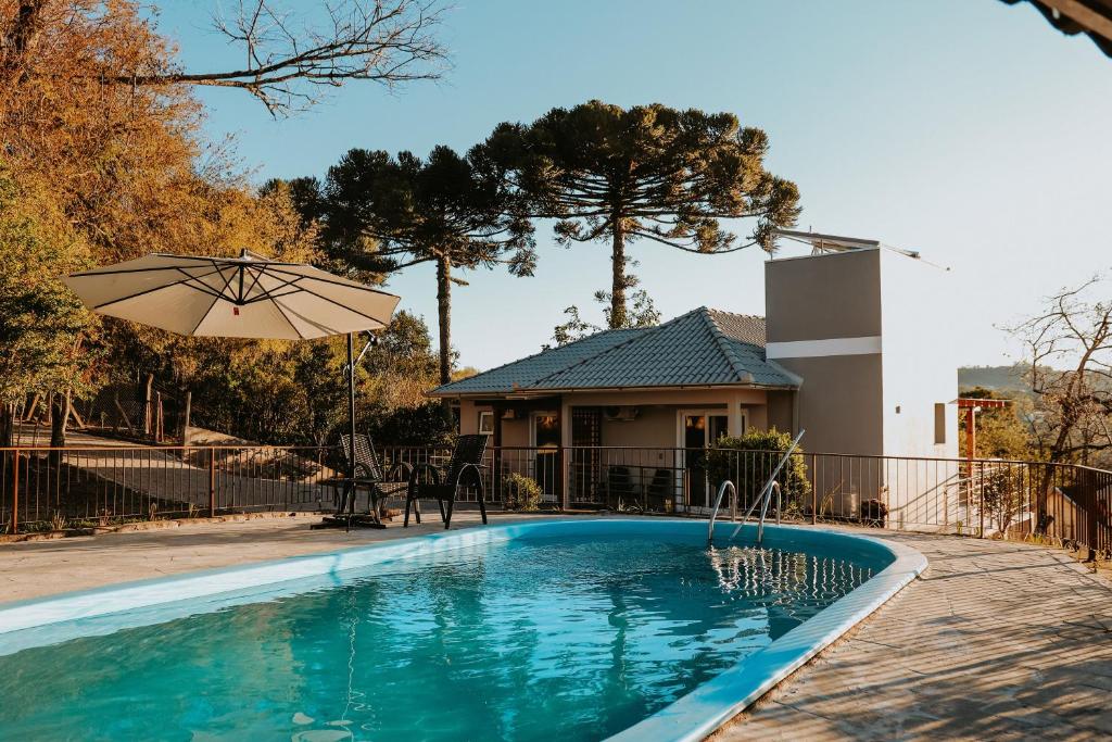 een zwembad met een parasol en een huis bij Alma do Vale Hospedaria in Bento Gonçalves