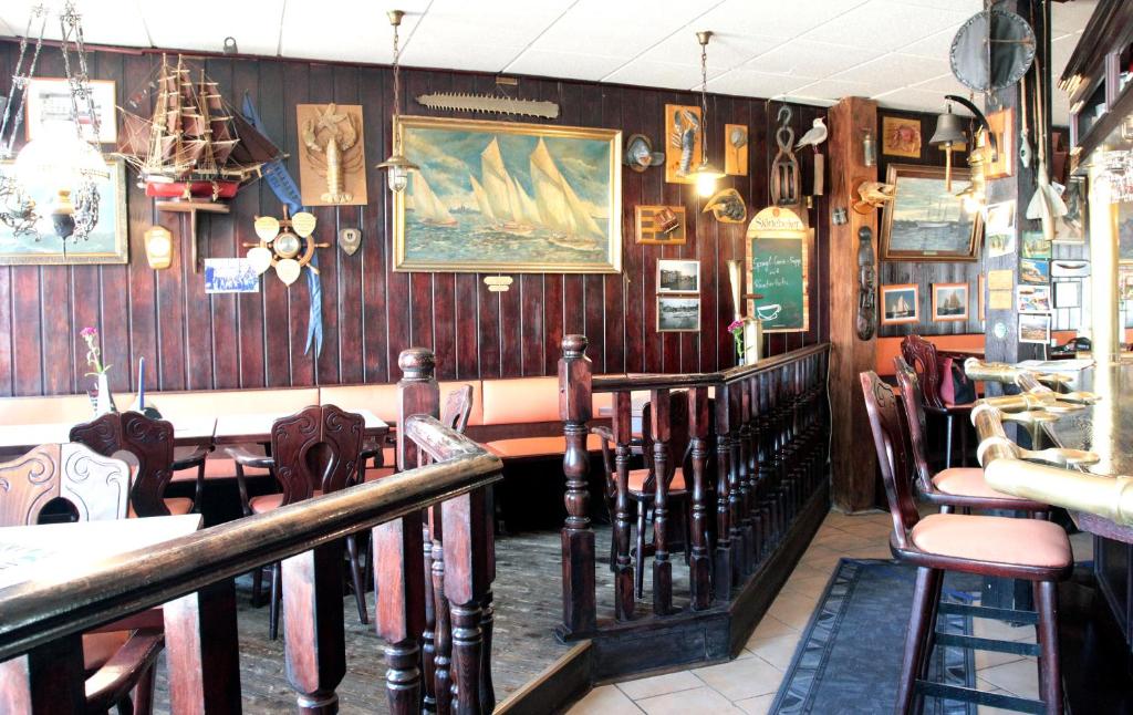 シュトラールズントにあるPension Klabautermannの木製の壁とテーブルと椅子が備わるレストラン