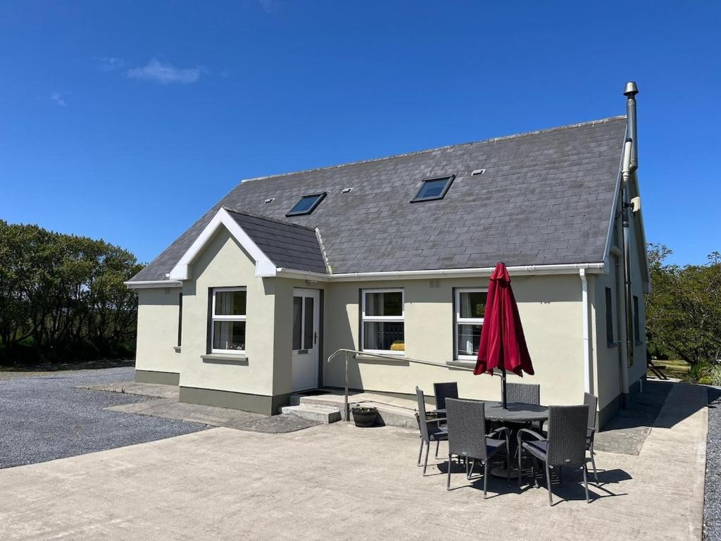 a house with a table and chairs and a red umbrella at Loophead SelfCatering Cottage SensoryAccessible in Kilrush