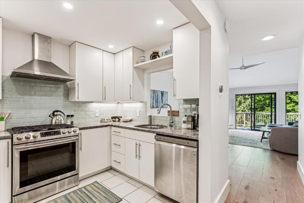a kitchen with white cabinets and stainless steel appliances at Rivercourt Condo D2 in Stowe