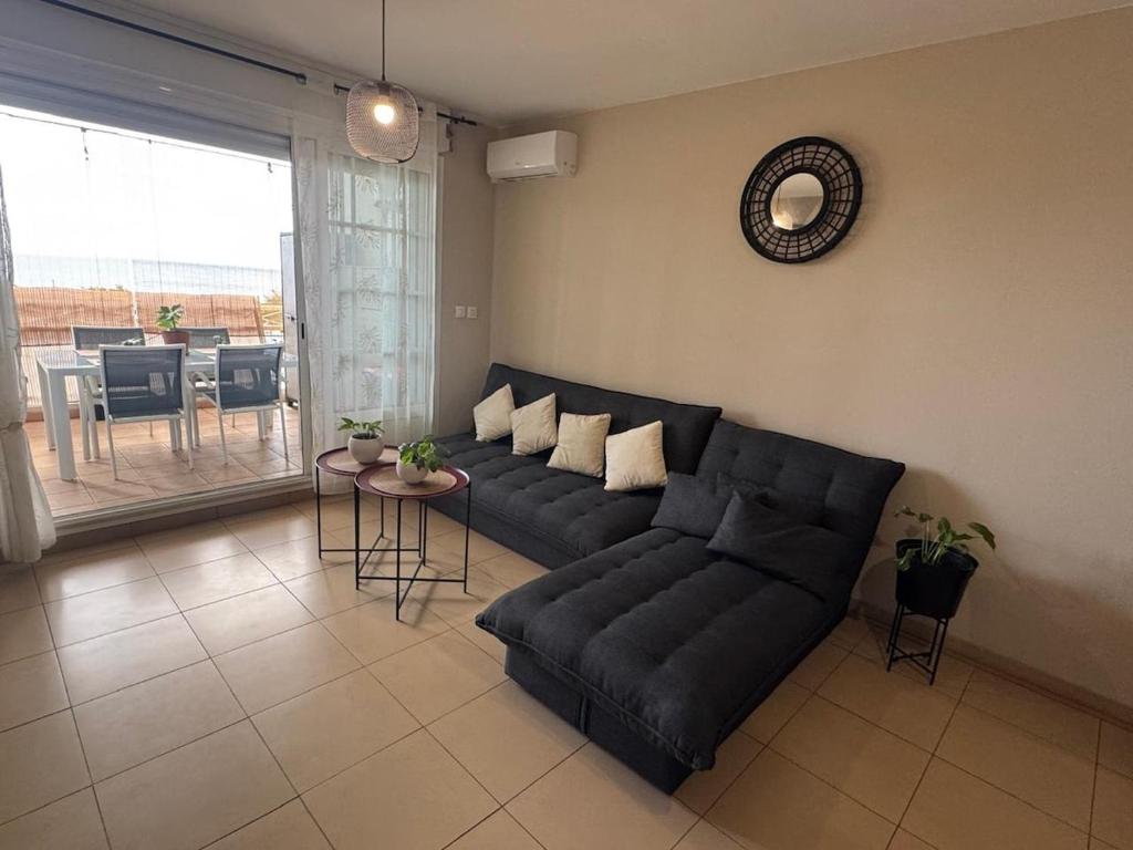 a living room with a black couch and a table at Rayon de vacances T3 spacieux et bien équipé in La Possession