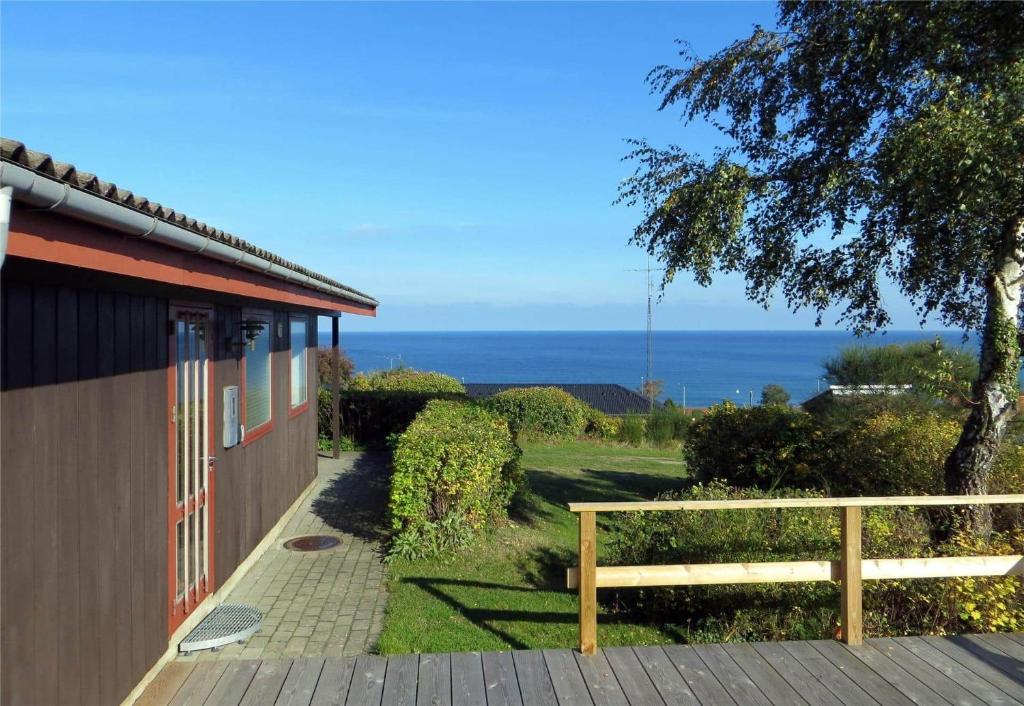 a wooden bench next to a building with a view of the ocean at 6682 Allinge - Brunekulvej 2 E in Allinge