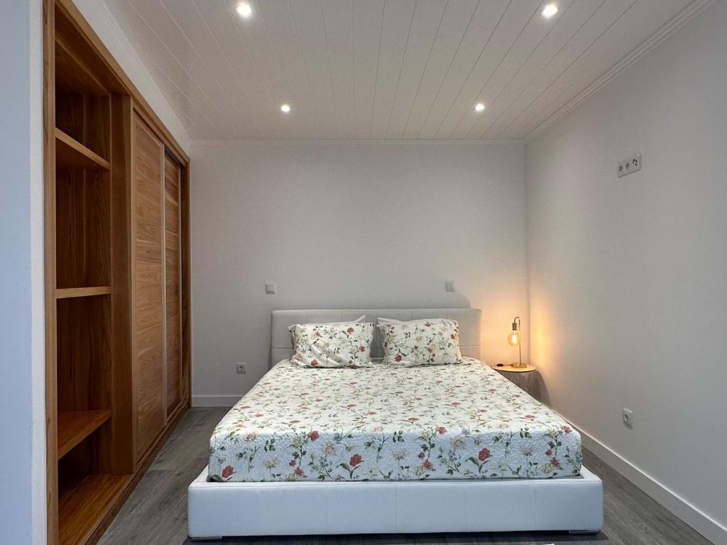 a white bedroom with a bed with two pillows at A Mercearia in Água de Pau