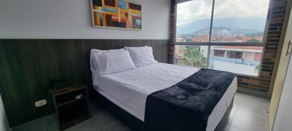 a bed in a room with a large window at La 70, Laureles Condo, Cold AC in Medellín
