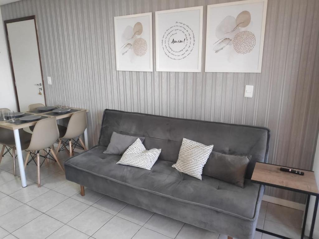 ein Sofa im Wohnzimmer mit einem Tisch und Stühlen in der Unterkunft Flat com piscina em Tambaú in João Pessoa