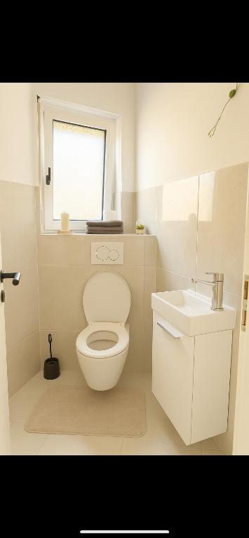 エッピンゲンにあるPetite Belleのトイレと洗面台を備えた白いバスルーム