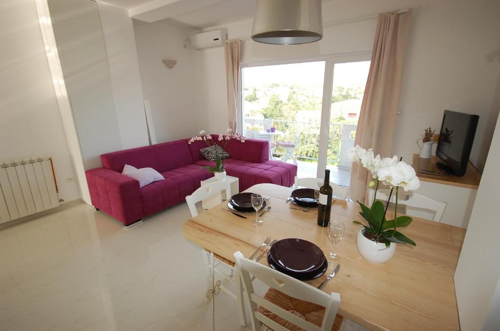 a living room with a table and a purple couch at Apartments Curicta 1 in Krk