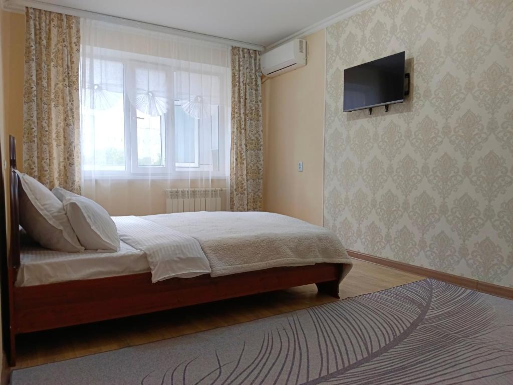 a bedroom with a bed and a window and a television at Nectar Apartments in Aktobe
