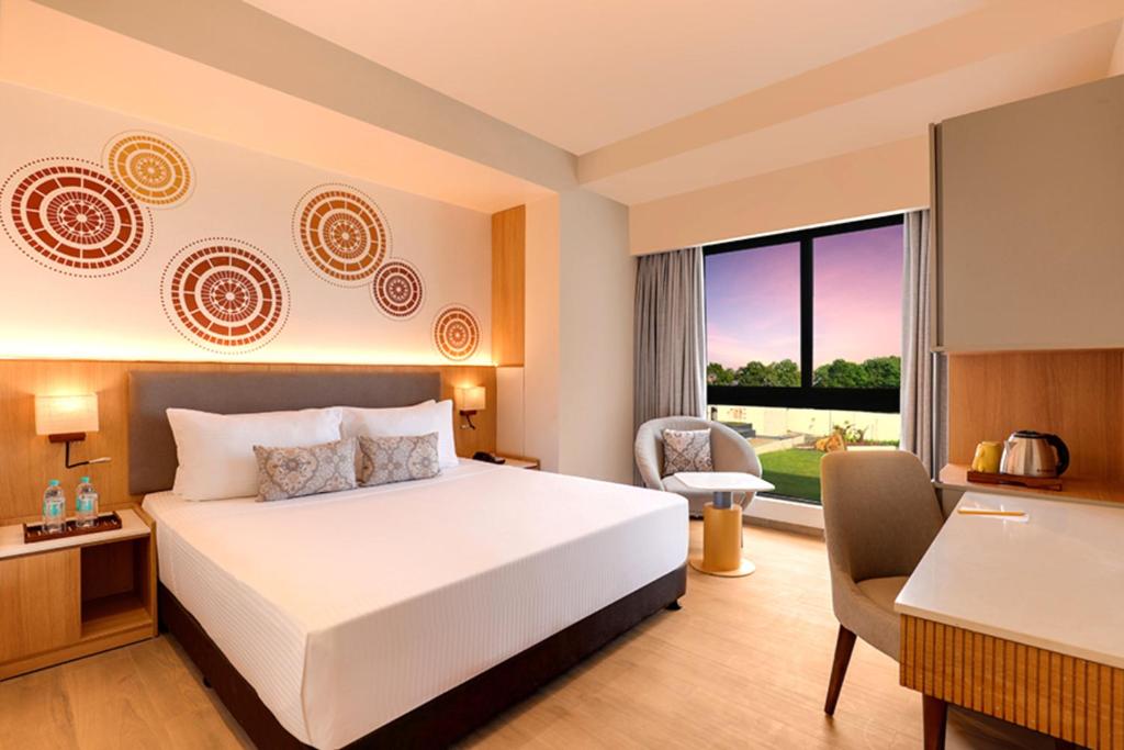 a hotel room with a bed and a desk and a window at Hotel Tela Suite plaza A Family Hotel- Delhi Airport Free Airport Drop in New Delhi