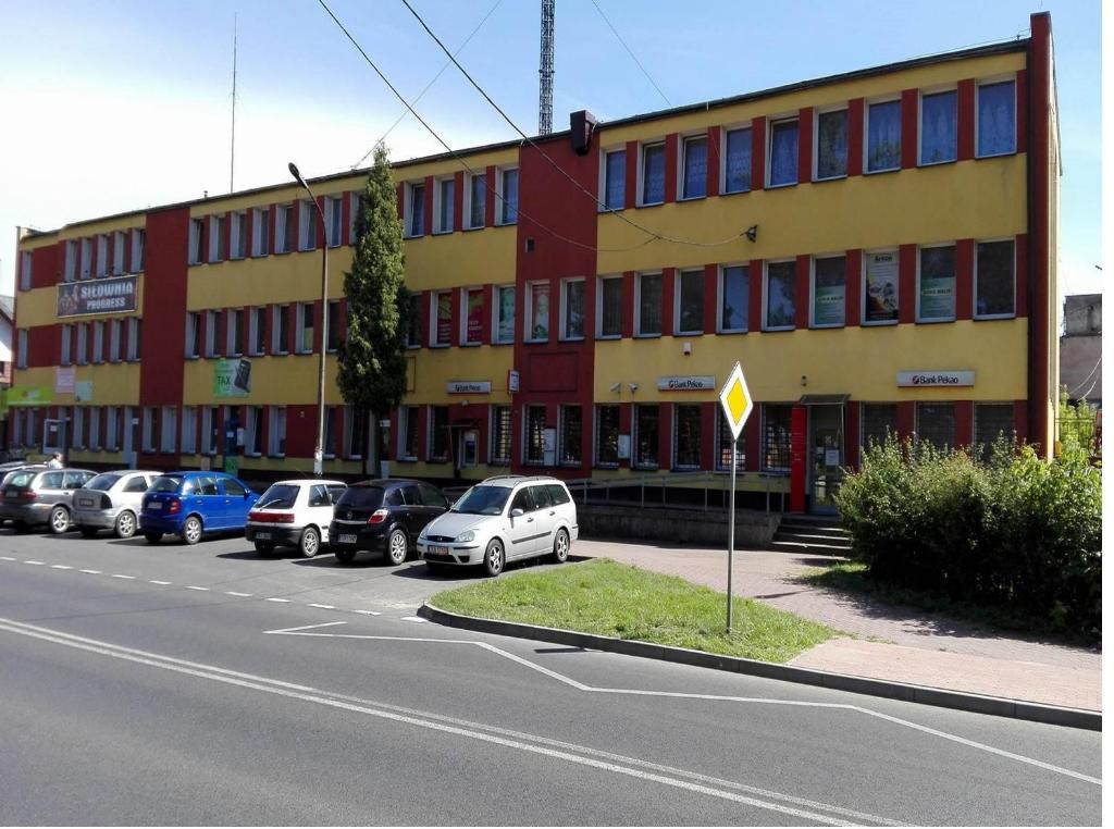 a large building with cars parked in a parking lot at Pokoje do wynajęcia Stąporków in Stąporków