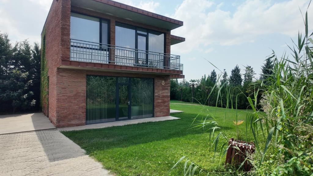 a brick house with a balcony on a lawn at Kachreti Ambassadori Golf Resort, 16 Villa in Kachretʼi
