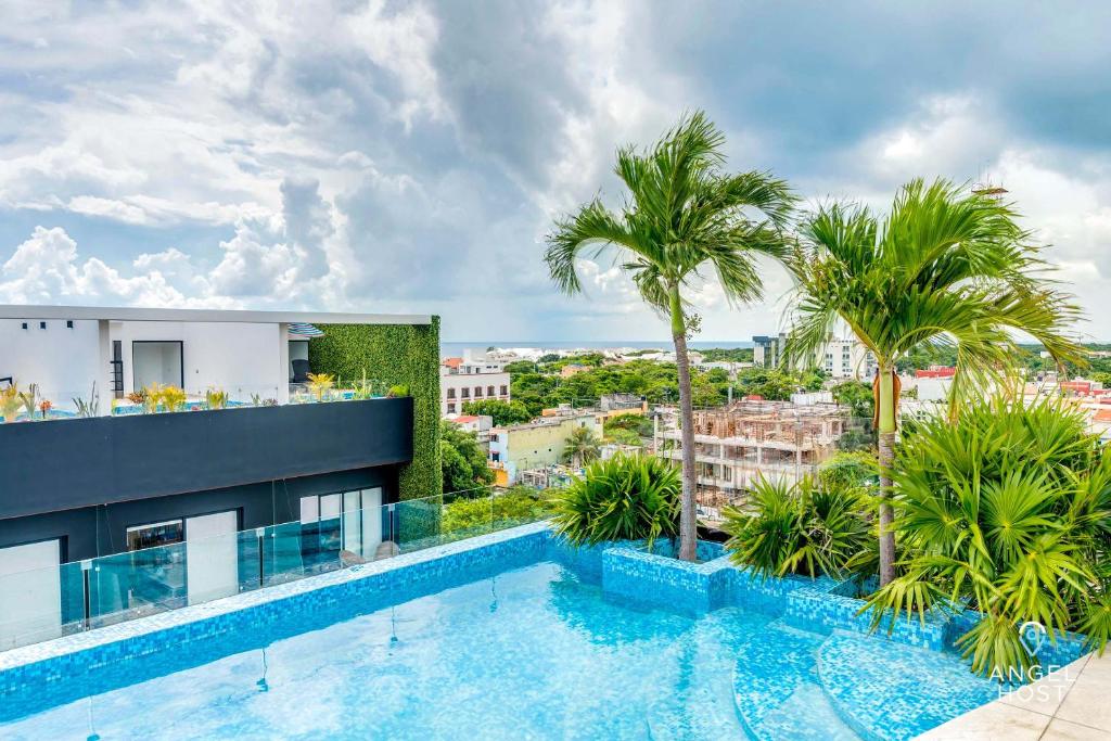 una piscina in cima a un edificio con palme di Adorable Rooftop Pool, Reliable WiFi, Near 5th Ave a Playa del Carmen