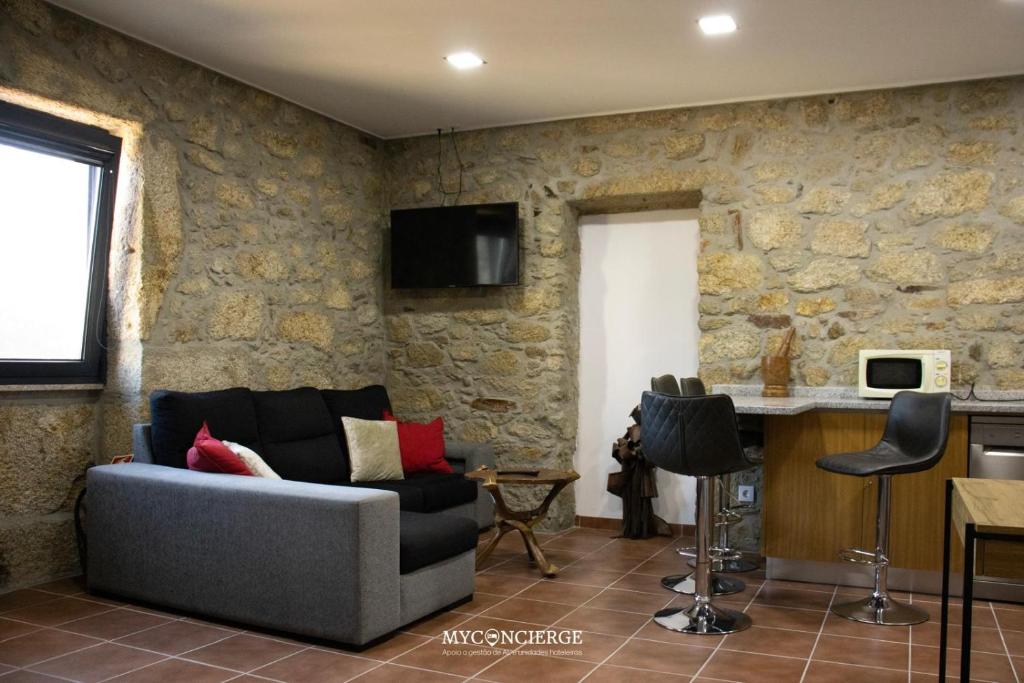 a living room with a couch and a stone wall at Quinta Dos Sonhos in Vale de Cambra