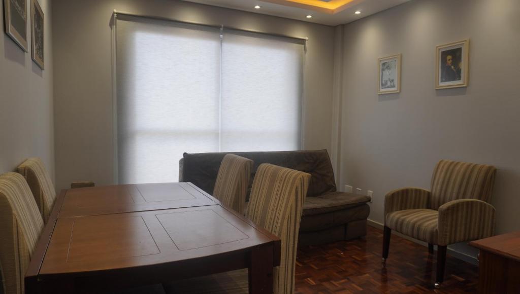 a living room with a table and a chair and a couch at Apartamento central próximo ao Shopping Palladium com garagem coberta in Ponta Grossa
