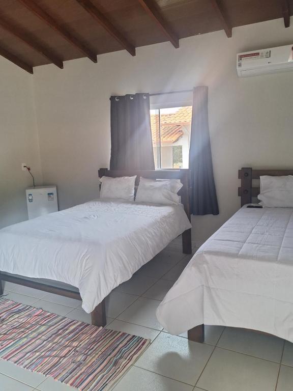 ein Schlafzimmer mit zwei Betten und einem Fenster in der Unterkunft Suítes Recanto das Flores 4 in Pirenópolis