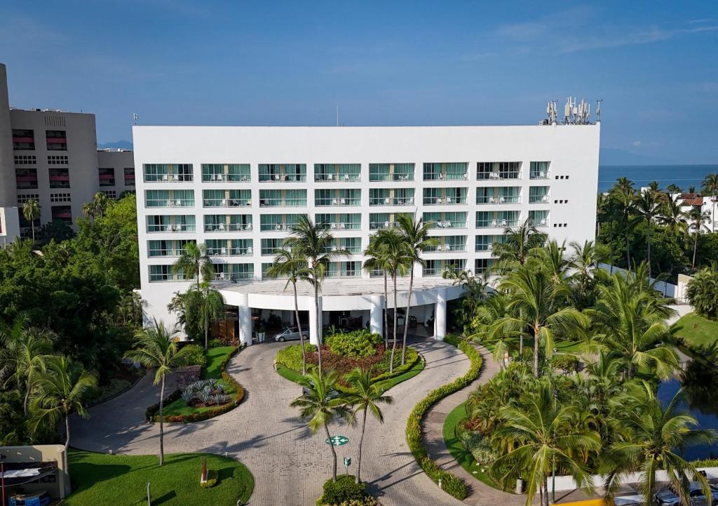 un grand bâtiment blanc avec des palmiers devant dans l'établissement Ocean Breeze Puerto Vallarta, à Puerto Vallarta
