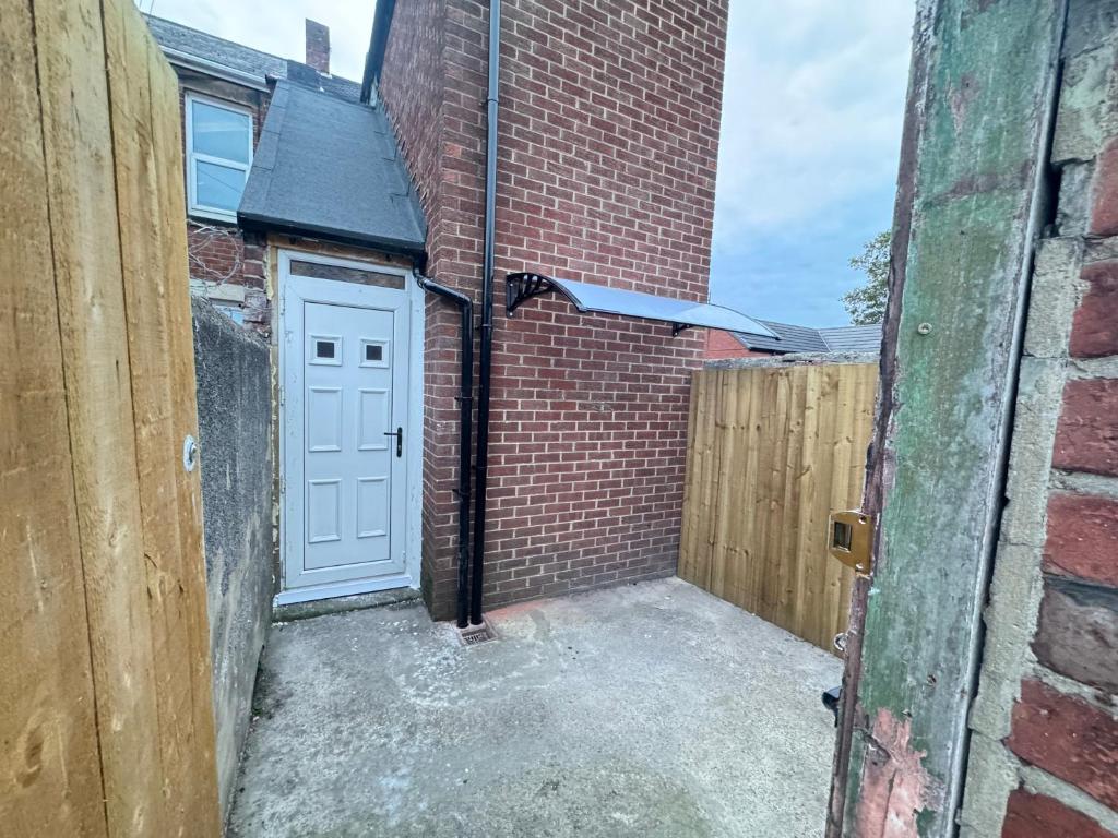 a garage with a white door and a brick wall at Jarrow Contractor & professional accommodation, Near port & hospital, 3bedroom apartment near Newcastle, free parking in Jarrow