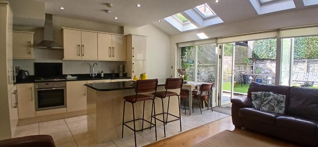 a kitchen with a bar with stools and a couch at Beautiful 3BD Home Beside Phoenix Park in Dublin