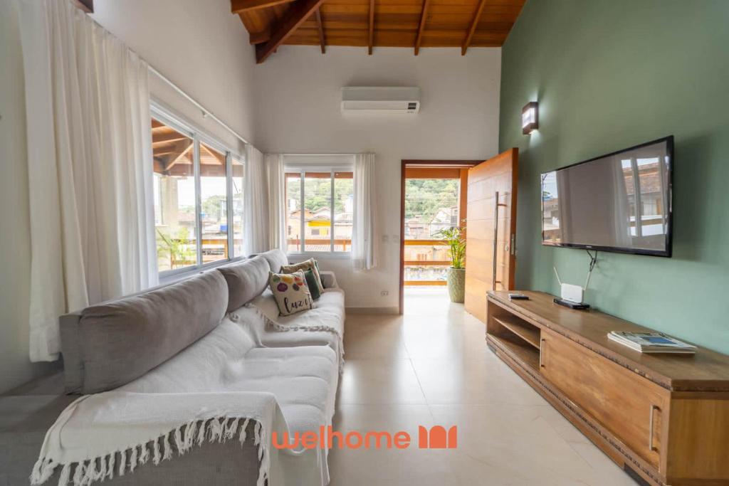 a living room with a couch and a flat screen tv at Casa em Maresias com Churrasqueira e area de lazer in Maresias