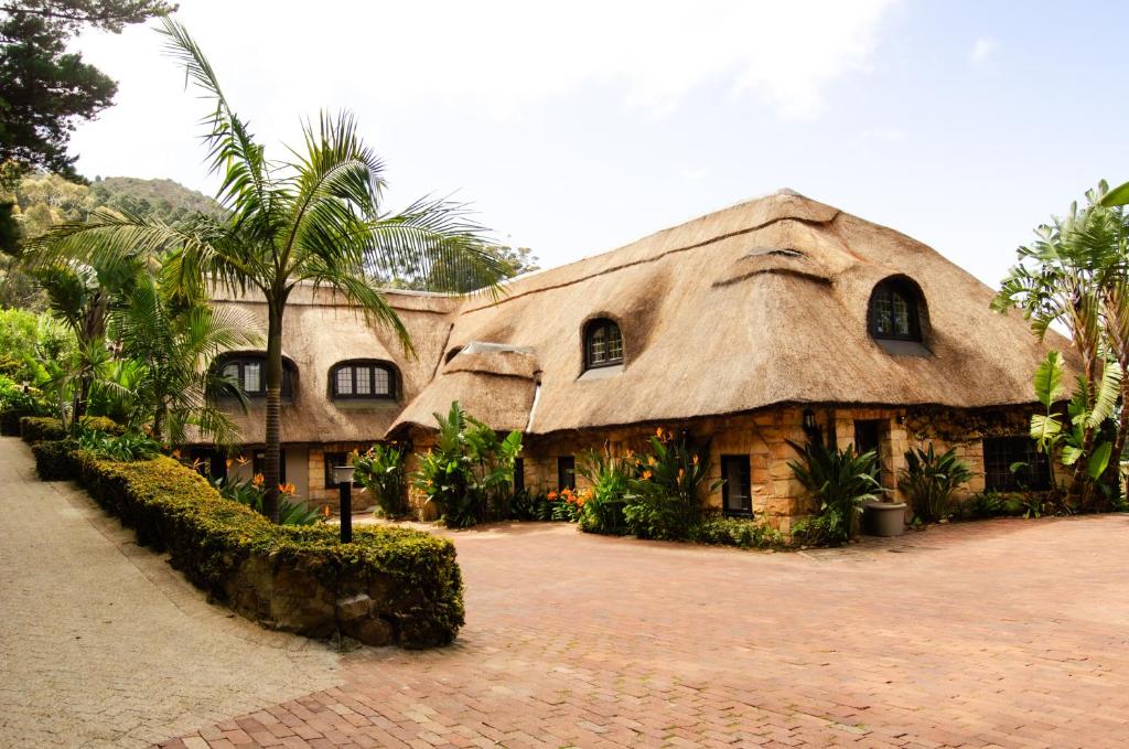 un edificio con techo de paja con palmeras en Ikhaya Safari Lodge, en Ciudad del Cabo