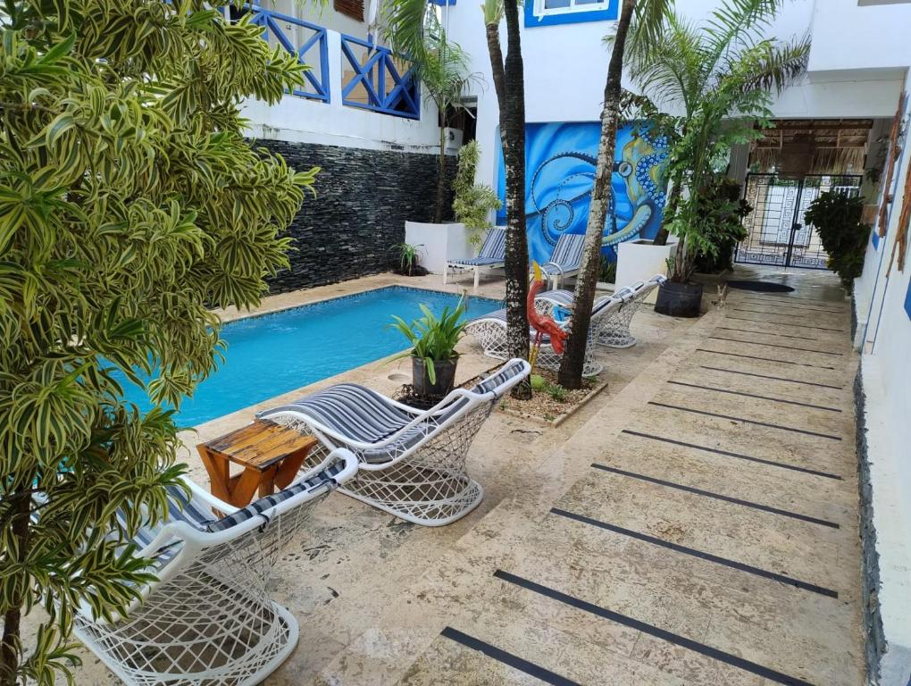 a pool with lounge chairs and a table and a building at Brisa de Alma Guesthouse in Bayahibe