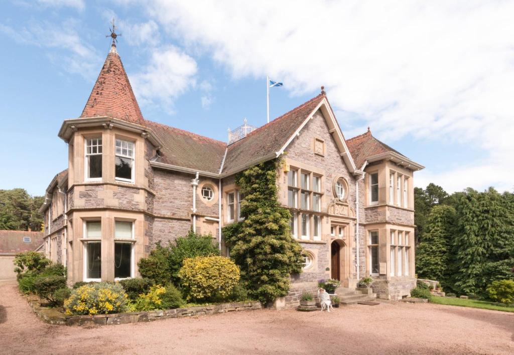 uma grande casa de pedra com uma torre em Firlands em Forres