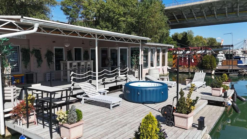 a wooden deck with chairs and a hot tub at Unique River Houseboat Stay in Železnička Stanica Senjak