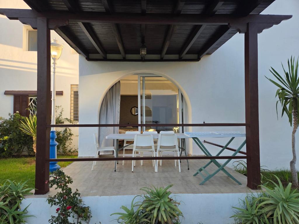 eine Terrasse mit Tisch und Stühlen unter einer Pergola in der Unterkunft Très Joli Appartement en résidence avec piscine in Cabo Negro