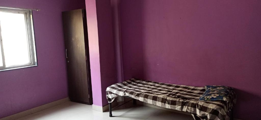 a room with a purple wall with a bed in it at Urvi Girls' Pg in Pune