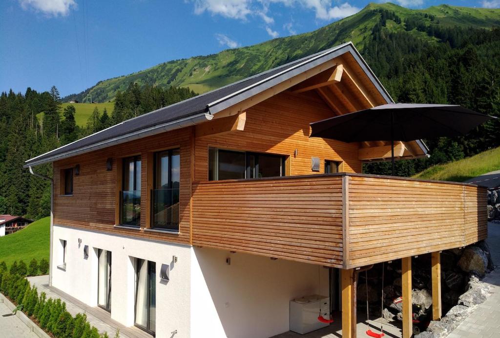 a house with a deck with an umbrella at Walser Berghaus in Riezlern