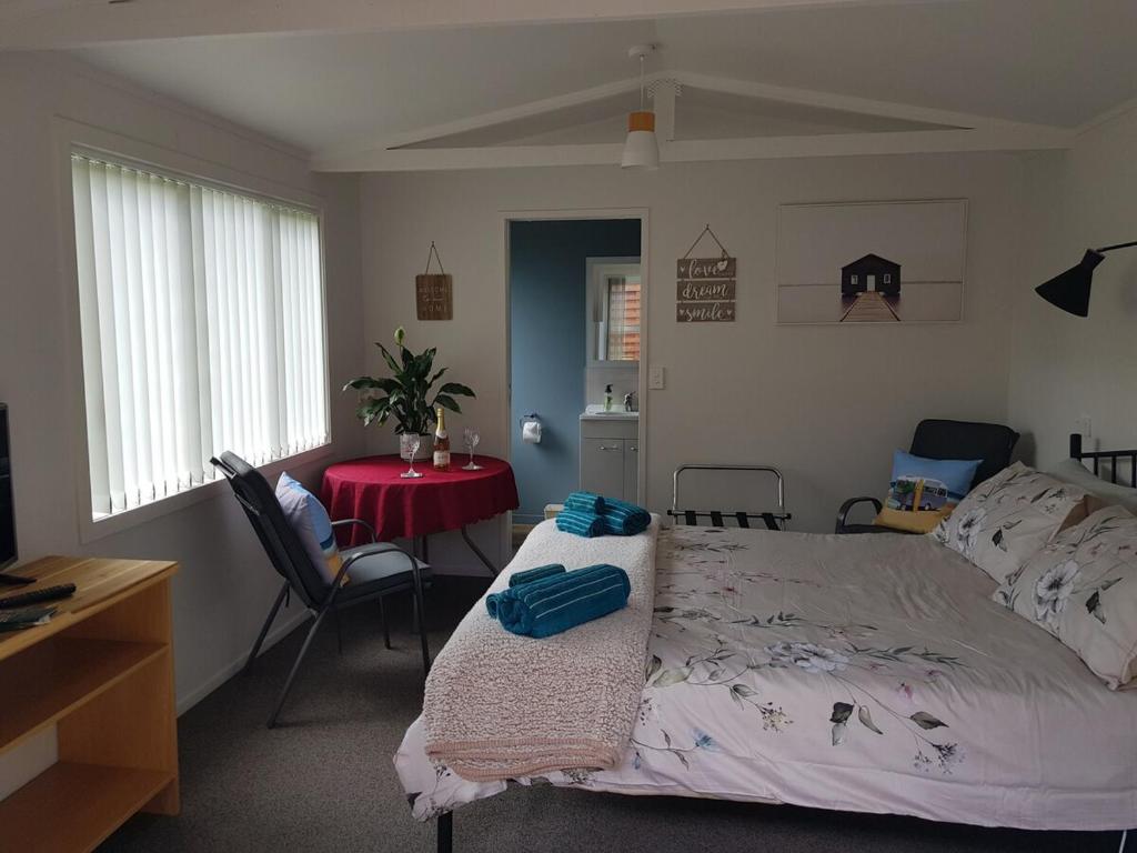 a bedroom with a bed and a table with a red table at Garden Studio in Rotorua