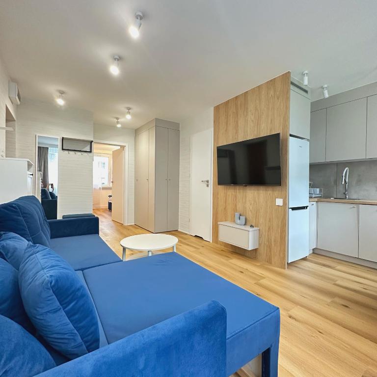 a living room with a blue couch and a kitchen at Apartament Blue in Bartoszyce