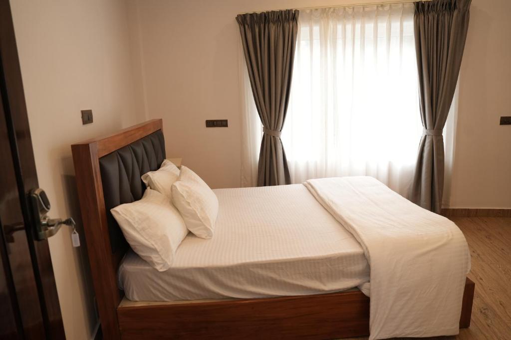 una camera da letto con un letto con lenzuola bianche e una finestra di Pallakki Comforts Chikmagalur a Attigundi