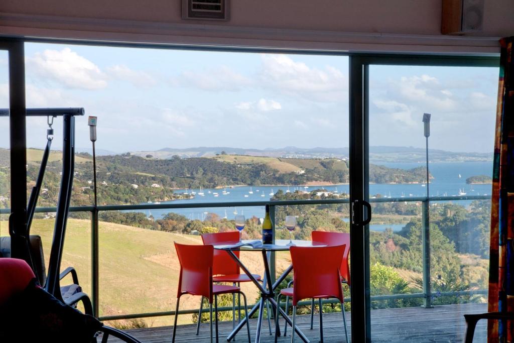 a table and chairs on a balcony with a view at Kereru Hill in Palm Beach