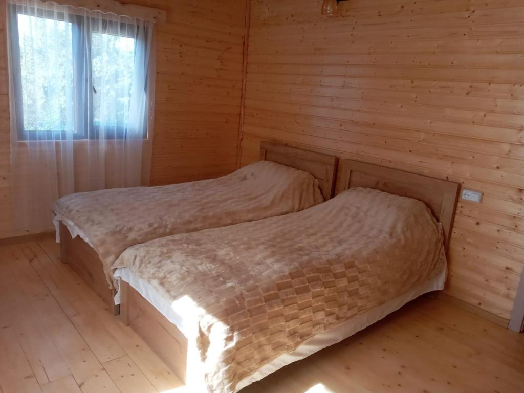 two beds in a log cabin with a window at Hotel Zghapari in Aspindza