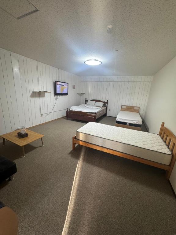 a room with two beds and a flat screen tv at Minpaku ayu B in Nago