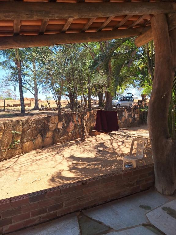 ein Tisch und ein Stuhl unter einer Steinmauer in der Unterkunft Suítes Recanto das Flores 2 in Pirenópolis