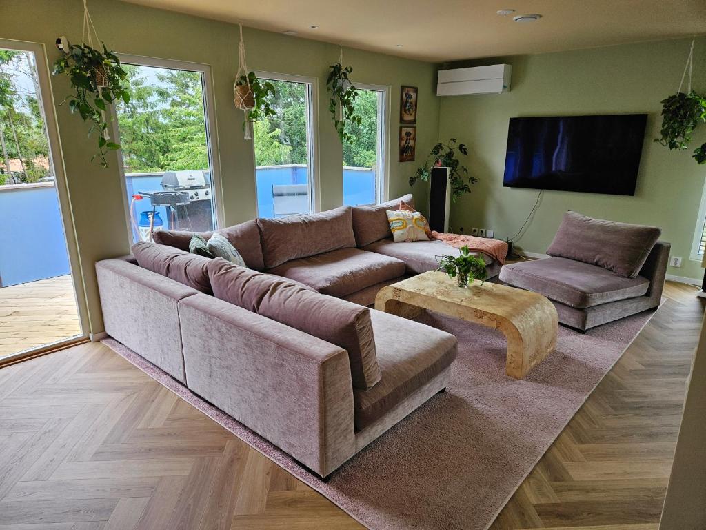 a living room with a large couch and a tv at Nyrenoverad stor villa 15 mintuer från Göteborg centrum in Västra Frölunda